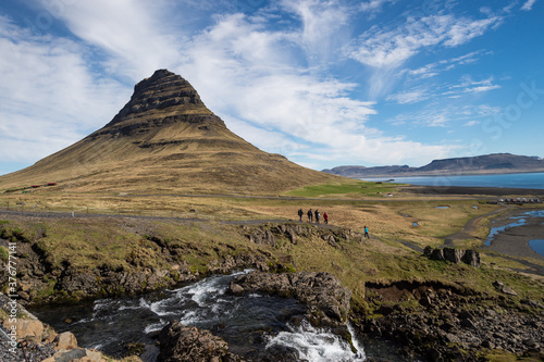 People walking in front of Kirkjufell mountain in West Iceland.