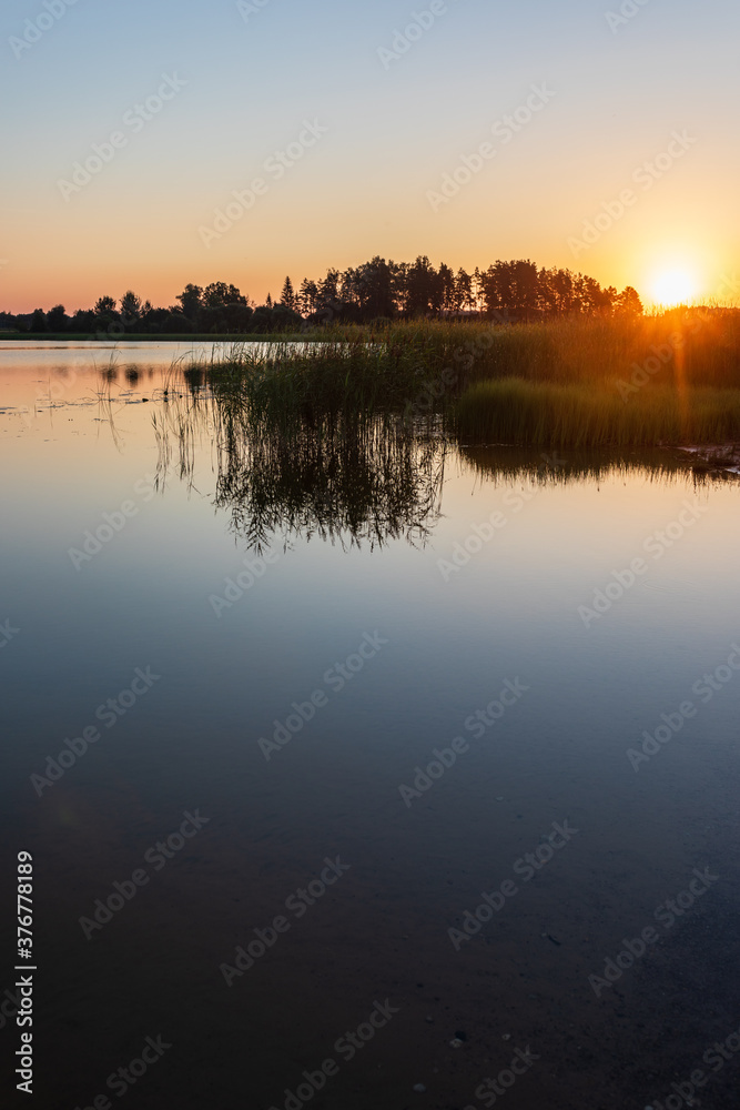 Sunrise over lake on a calm, peaceful morning, with forest in afar