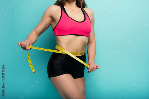 Determinated Sport woman has an excellent physical shape and measure with the meter. Cyan background