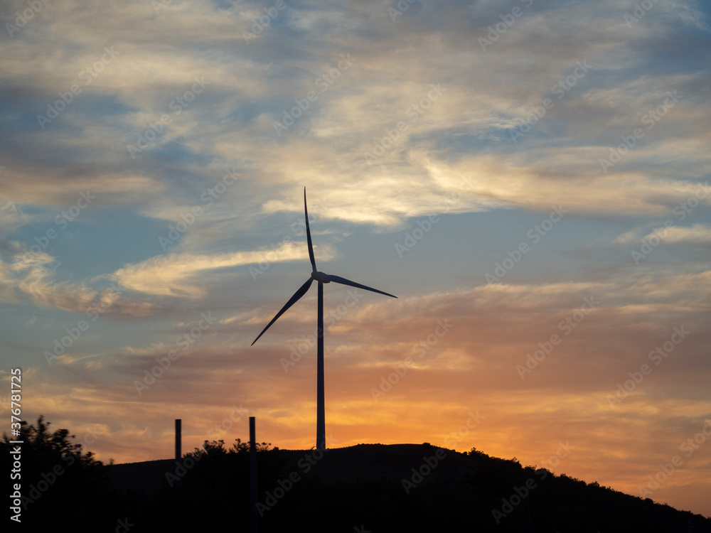 Obraz premium Molinos de vientos en una montaña durante la puesta de sol