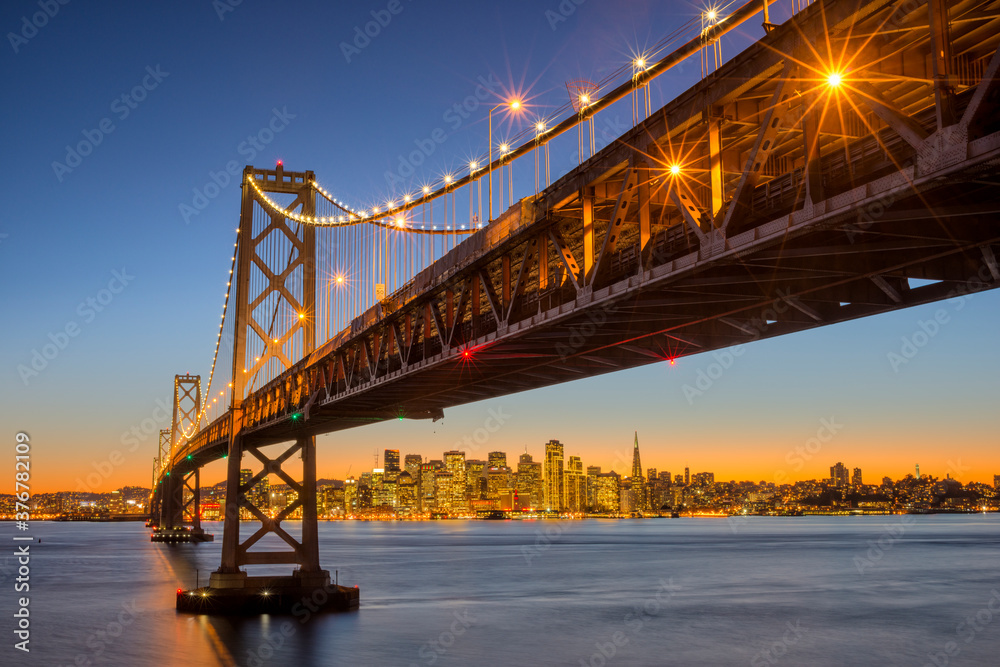 Scenic view of San Francisco Oakland Bay Bridge with downtown during sunset Scenic view of San Francisco Oakland Bay Bridge with downtown during sunset