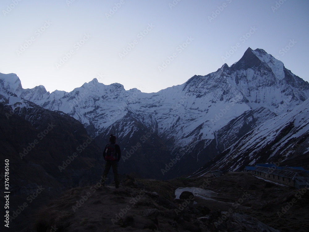 A climber standing in front of a snow-covered rock in the early morning, ABC (Annapurna Base Camp) Trek, Annapurna, Nepal