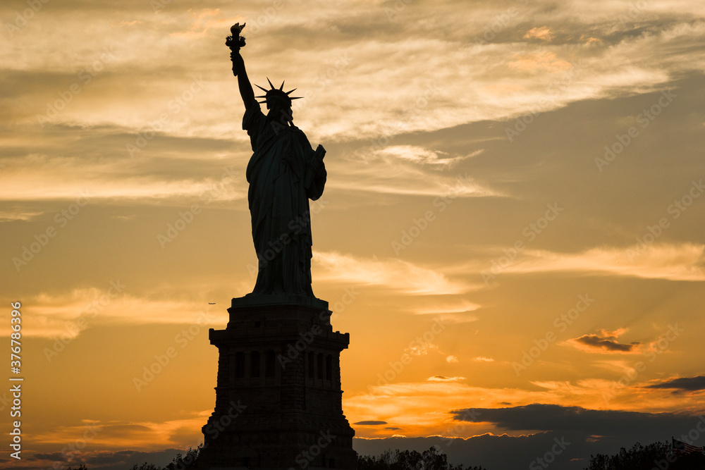 Silhouette of Statue of Liberty against cloudy sky during sunset Silhouette of Statue of Liberty against cloudy sky during sunset