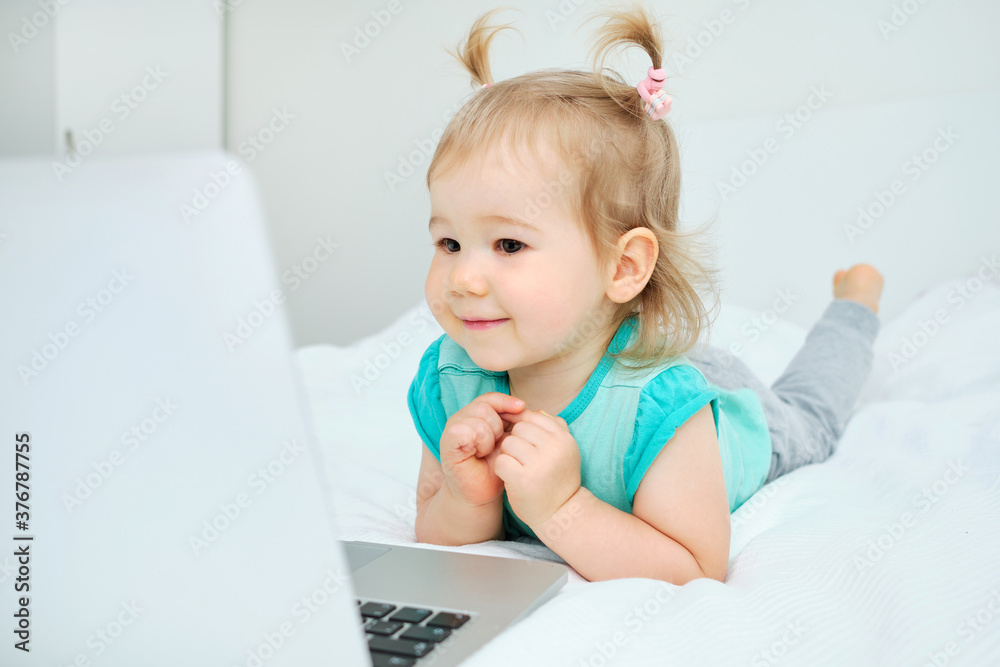 Happy smiling caucasian toddler girl playing on laptop