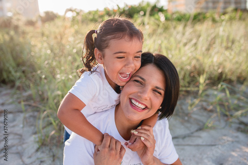Mom and daughter on the beach running around and having fun 

