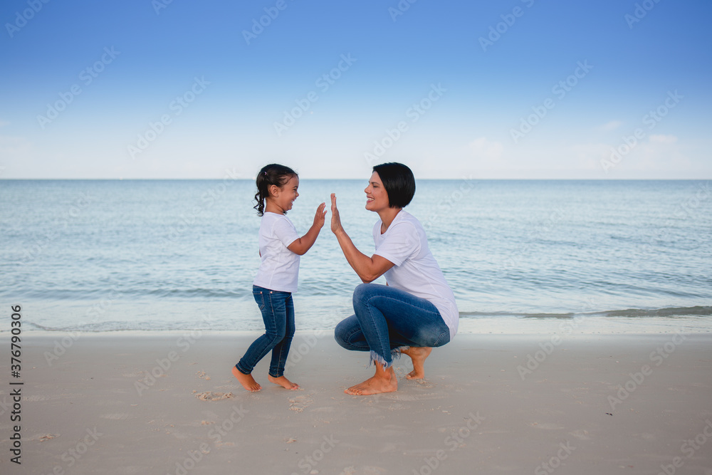 Mom and daughter on the beach high five Mom and daughter on the beach high five