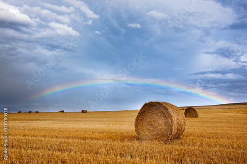 Scenic view of rainbow over field with hay bales photo