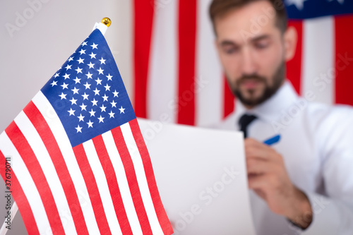 An American official reads documents against the background of the US flag. Approval of documents with American government agencies. Immigration to the USA. Work in America.