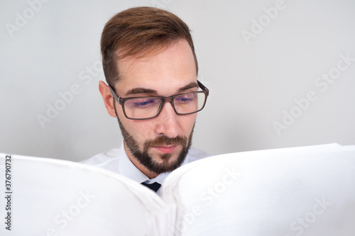 Fototapeta Naklejka Na Ścianę i Meble -  A man with glasses reads documents. A person studies regulations. The auditor conducts an audit. The teacher is preparing for the lecture.