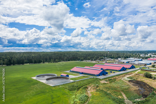 Aerial view of a farm with red roofs in a field with green grass