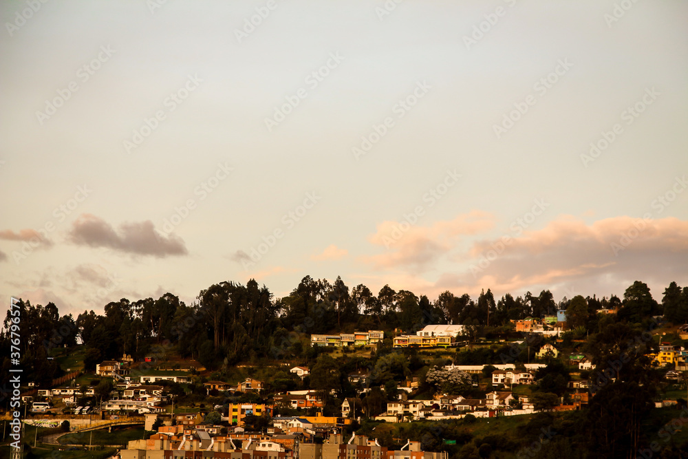 sunset in Bogota, pinetrees, houses, orange clouds, blue sky