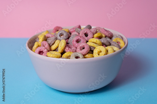 Isolated bowl of mixed cereals and marshmallows on a blue and pink background