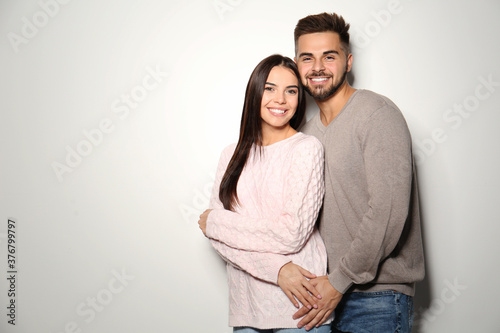 Lovely couple in warm sweaters on light background. Space for text