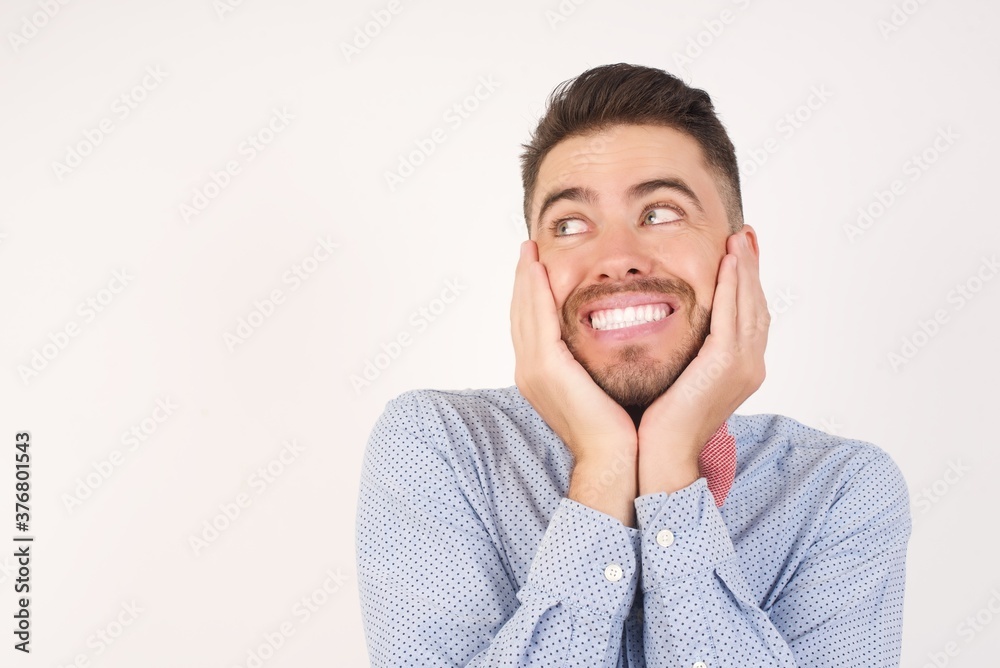 Inspired European man dressed in formal shirt and bow tie poses against white background looking at copyspace having thoughts about future events Inspired European man dressed in formal shirt and bow tie poses against white background looking at copyspace having thoughts about future events