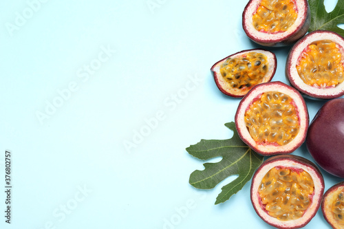 Fresh ripe passion fruits (maracuyas) with green leaves on light background, flat lay. Space for text