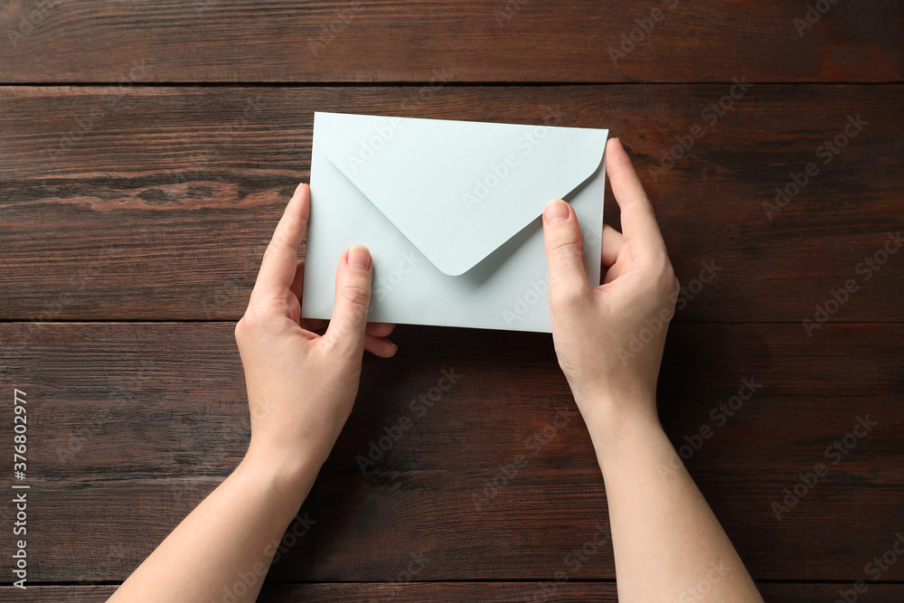 Woman with white paper envelope at wooden table, top view Woman with white paper envelope at wooden table, top view