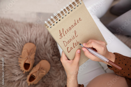 Pregnant woman writing baby names list, closeup photo