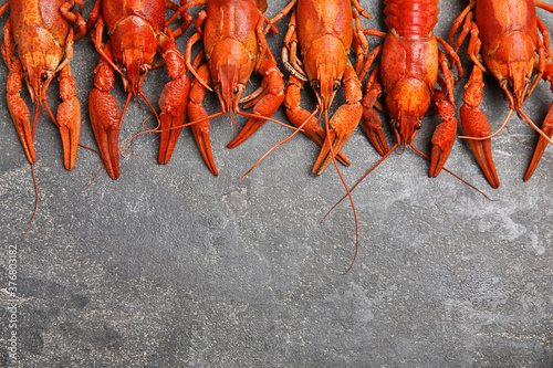 Delicious boiled crayfishes on grey table, flat lay. Space for text