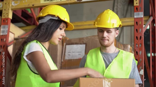 Warehouse workers in helmet and vest packing parcel box in warehouse  