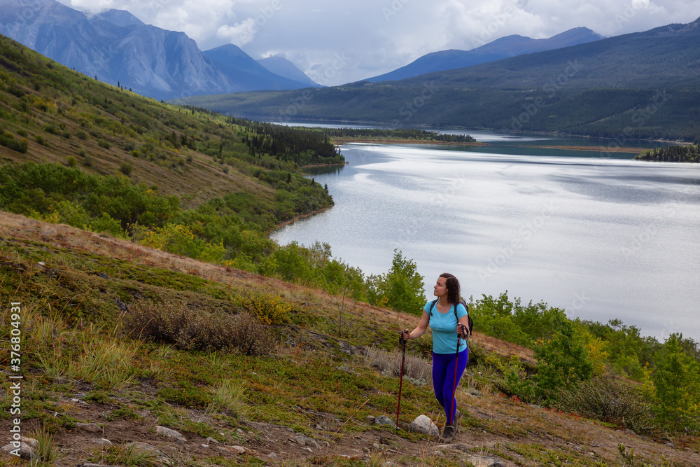 Adventurous Girl Hiking up the Nares Mountain during a cloudy and sunny evening. Taken at Carcross, near Whitehorse, Yukon, Canada.