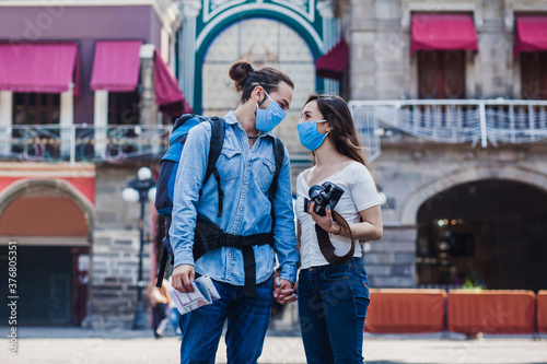Tourist couple in a historical latin american city with face mask holding a camera on vacation in coronavirus pandemic © Marcos