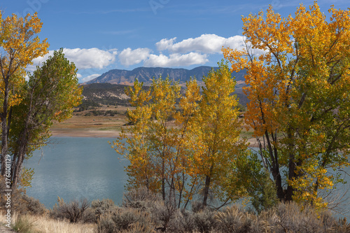 Autumn lake in western Colorado with golden trees in the foreground and mountains in the distance/