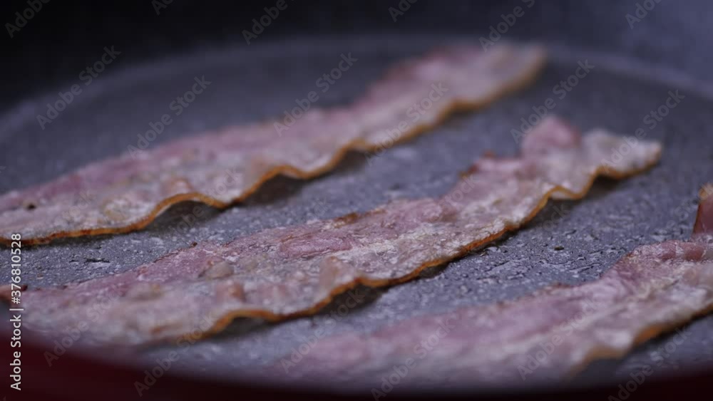 Bacon cooking in frying pan, extreme close up, high angle shallow focus.