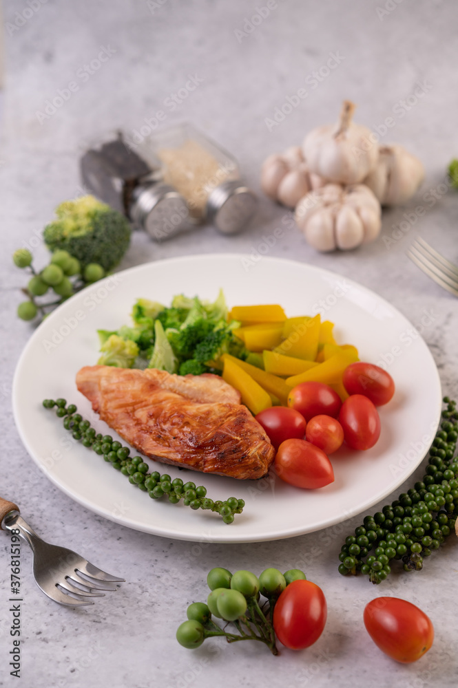 Chicken steak topped with white sesame, peas, tomatoes, broccoli and pumpkin in a white plate. Chicken steak topped with white sesame, peas, tomatoes, broccoli and pumpkin in a white plate.