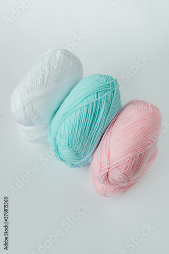acrylic soft pastel pink, azure and white colored wool yarn thread skeins row on white background, top view, vertical stock photo image with copy space for text