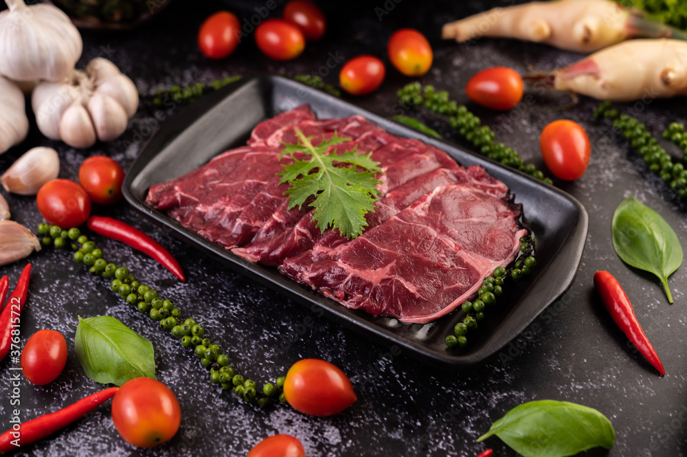 Sliced ​​raw pork used for cooking with chili, tomato, basil, and fresh pepper seeds.