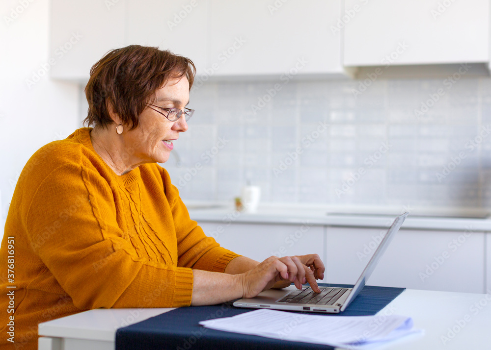 Smiley elder woman working with laptop at home. Smiley elder woman working with laptop at home.