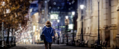 A woman walks through the city night scene landscape.