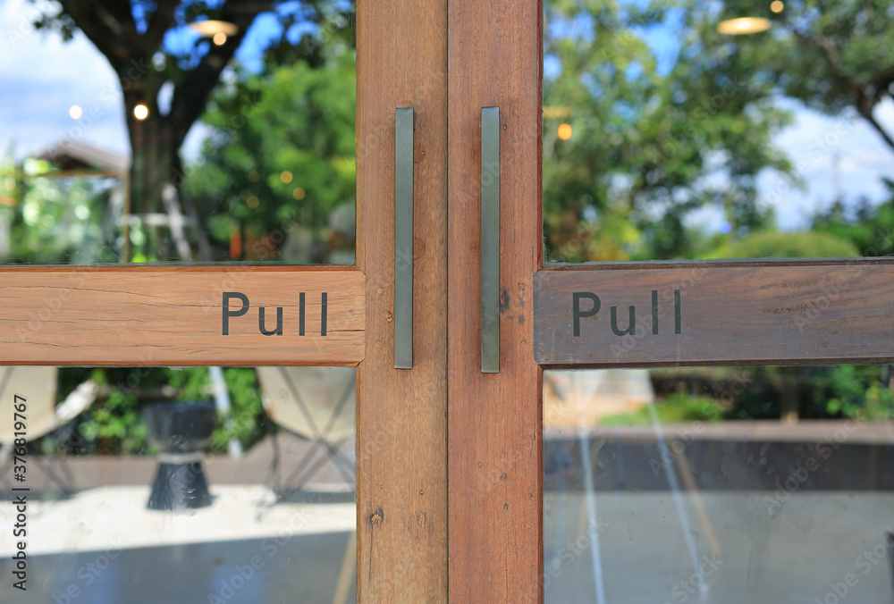 Fototapeta premium Glass door of restaurant with text pull on wood.