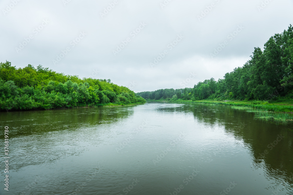 Calm river with trees on the shores in rainy summer day. Summer landscape. Calm river with trees on the shores in rainy summer day. Summer landscape.