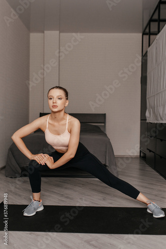 beautiful caucasian woman in sportswear stretches her legs on the mat at home before starting workout. health care concept. © Виталий Римдейка