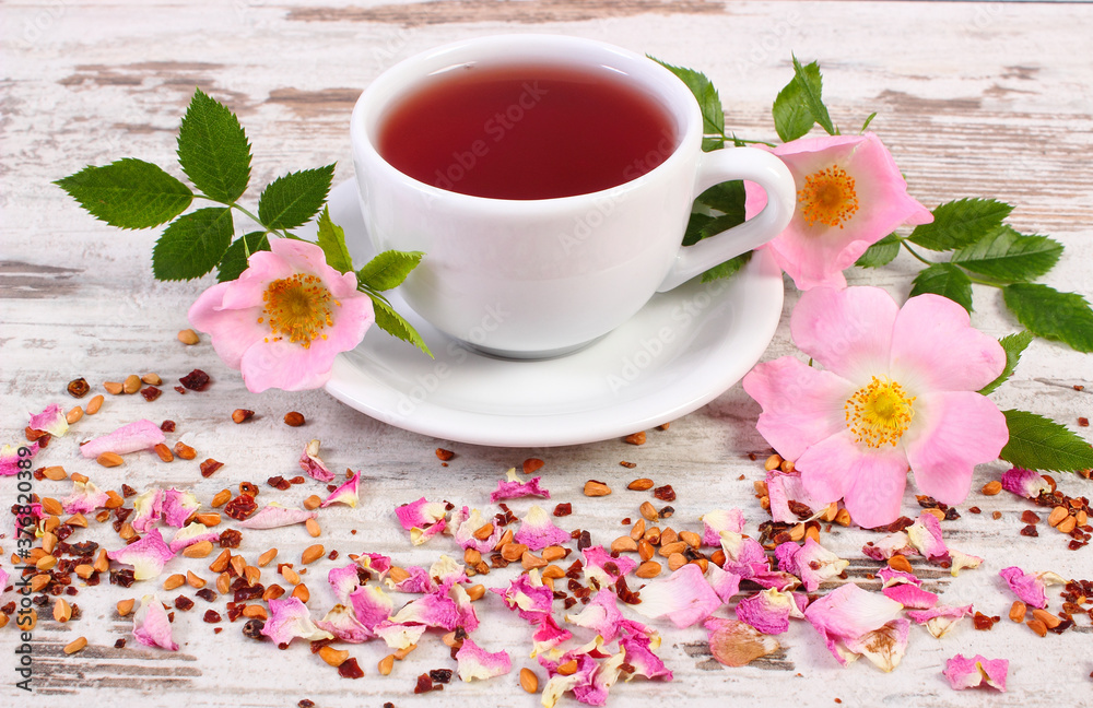 Cup of tea with wild rose flower on old rustic wooden background Cup of tea with wild rose flower on old rustic wooden background