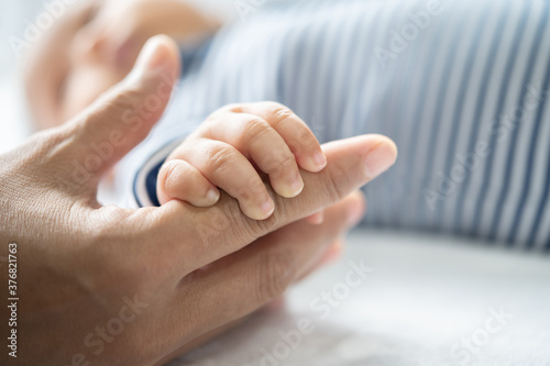 The hand of the newborn baby that holds the fingers of the mother