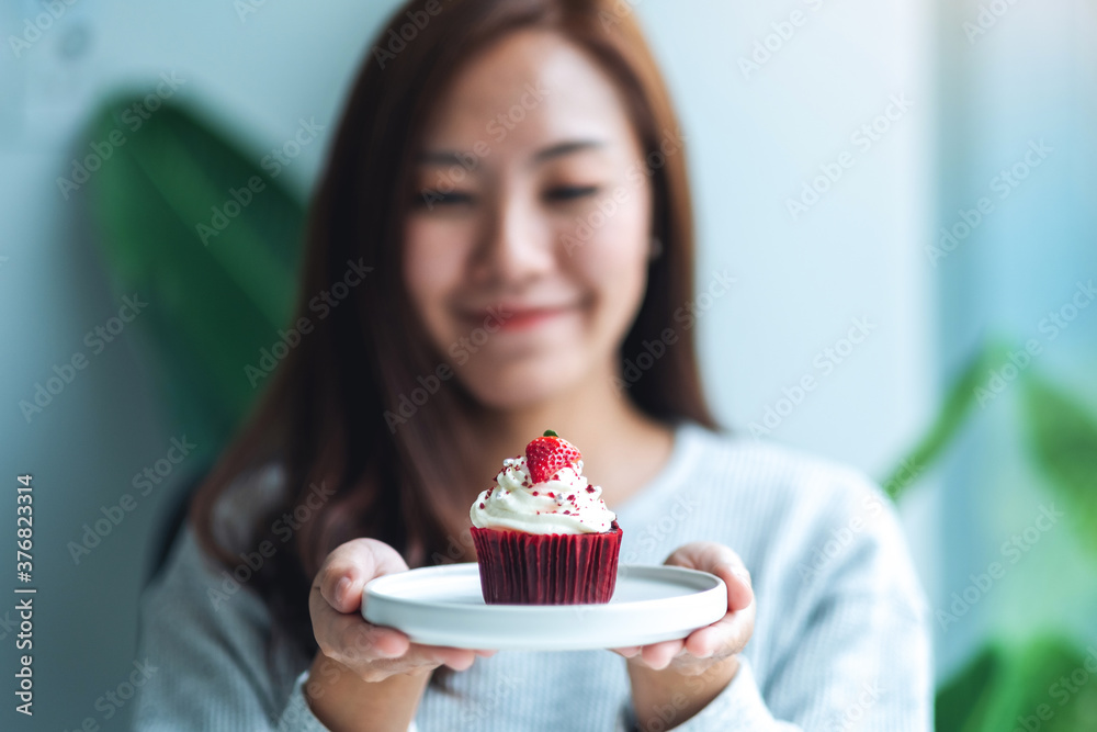 A beautiful asian woman holding a plate of red velvet cup cake A beautiful asian woman holding a plate of red velvet cup cake