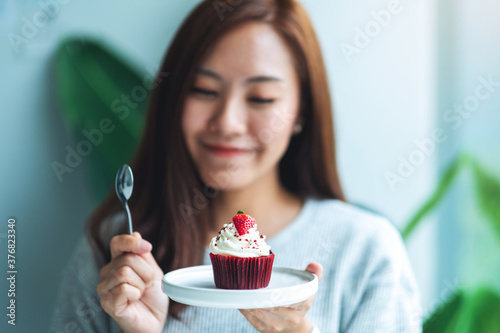 Canvas Print A beautiful asian woman holding and eating a red velvet cup cake
