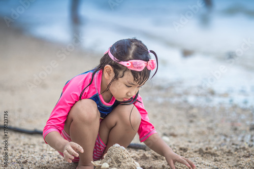 Close-up background view of an Asian girl, playing in the sea on the beach, with a parent or guardian supervising during the holidays, family getaways.