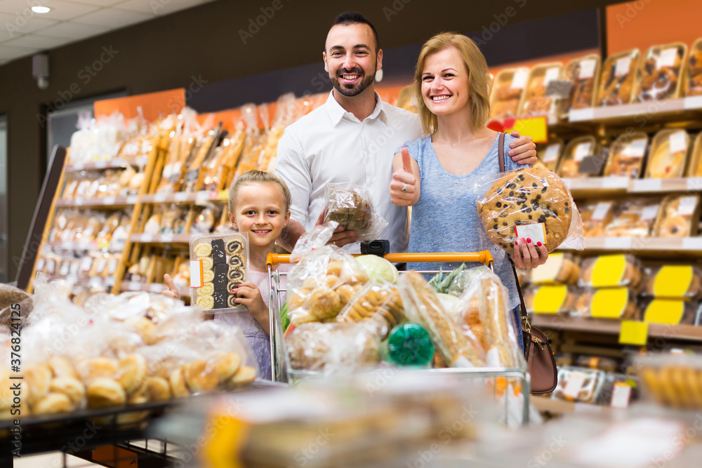 Portrait of family choosing bread and sweets in bakery section in supermarket.