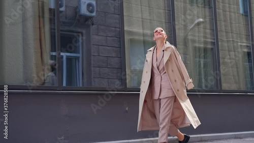 Wallpaper Mural A young woman with short hair in a suit and raincoat is smiling, dancing, walking down the street in the business part of the city. Torontodigital.ca