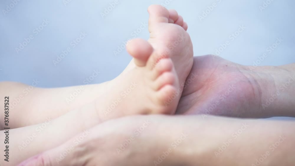 Happy family. Mother's hands hold the baby's legs. The legs of a newborn baby are caressed by a mother. Happy family. Mother's hands hold the baby's legs. The legs of a newborn baby are caressed by a mother.