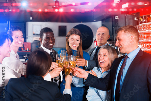 Happy colleagues clinking glasses of champagne on corporate party