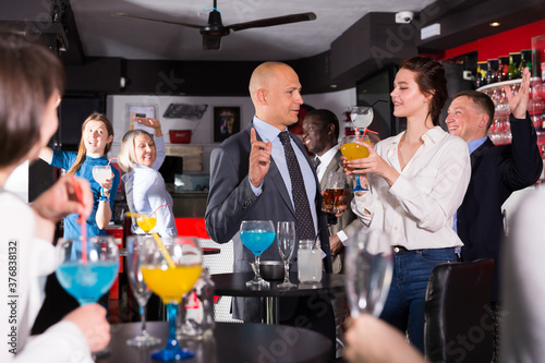 Friendly coworkers having pleasant conversation and flirting during office party at nightclub