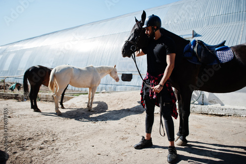 Arab tall beard man wear in black helmet with arabian horse.