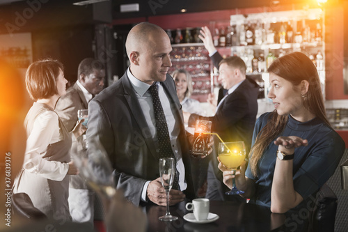 Friendly coworkers having pleasant conversation and flirting during office party at nightclub