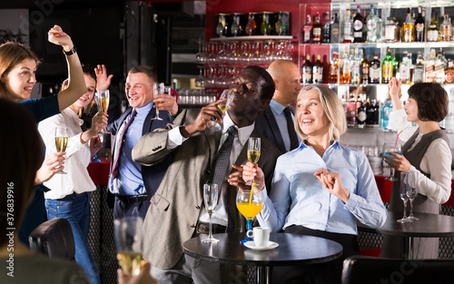 Cheerful African businessman having fun with mature female coworker during office party at nightclub