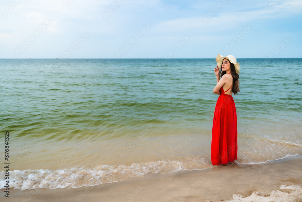 happy woman in red dress standing with arms crossed on sea beach happy woman in red dress standing with arms crossed on sea beach