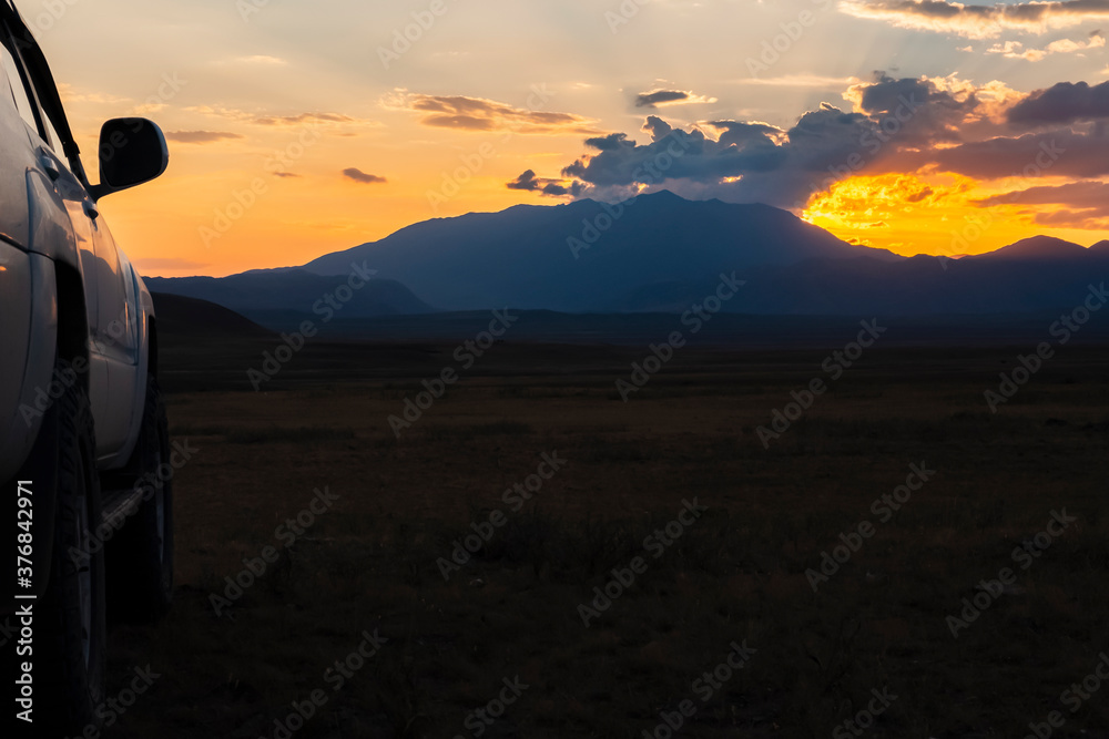 Sunset with suv and mountains silhouette on background. Adventure travel. Tourism concept. Offroad car. Road trip, journey concept.